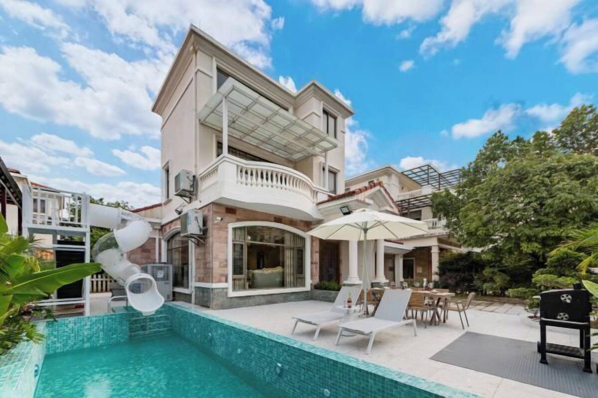 Une maison moderne à deux étages dotée d’une piscine, d’un espace salon extérieur et d’un patio couvert.