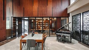 Une pièce spacieuse comprenant un piano, une table à manger avec des chaises et une grande cloison en verre.