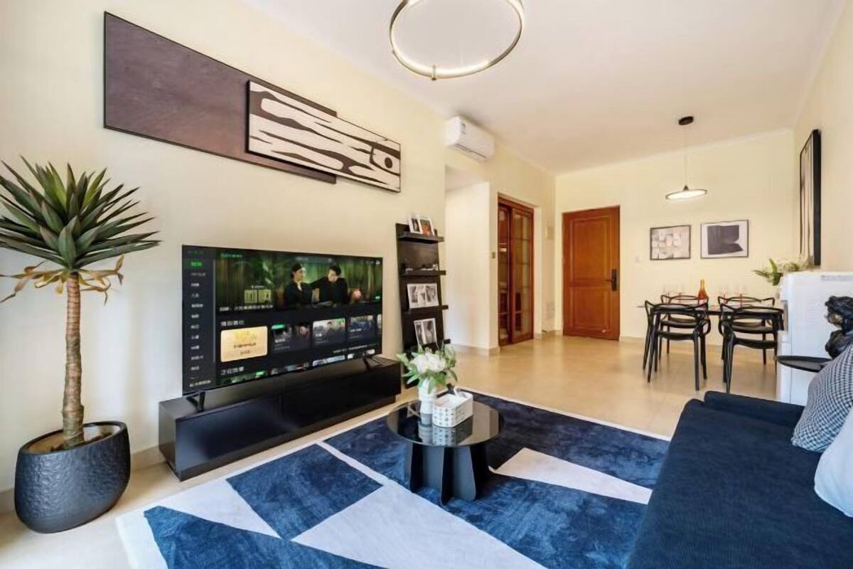 Un salon moderne avec un téléviseur à écran plat, une table basse et un canapé. Il y a également un coin repas avec une table et des chaises.