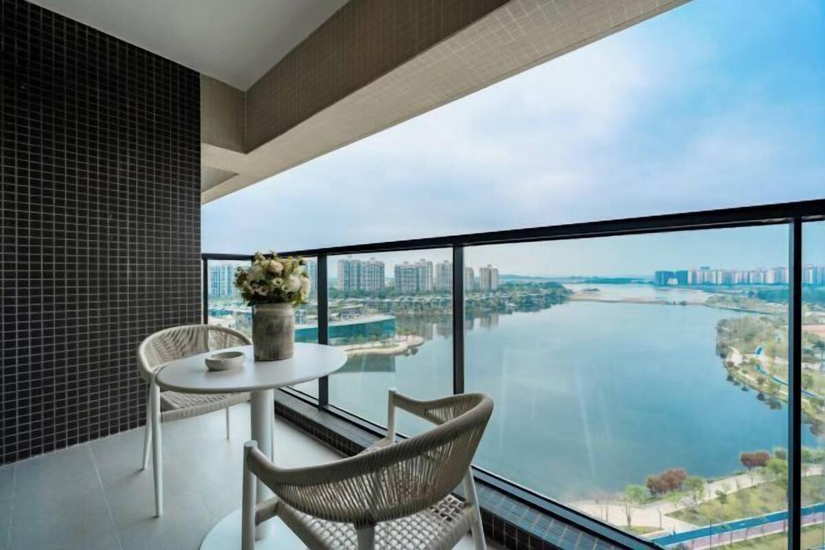 Un balcon offrant une vue sur une rivière et le paysage urbain, aménagé avec une table et des chaises.