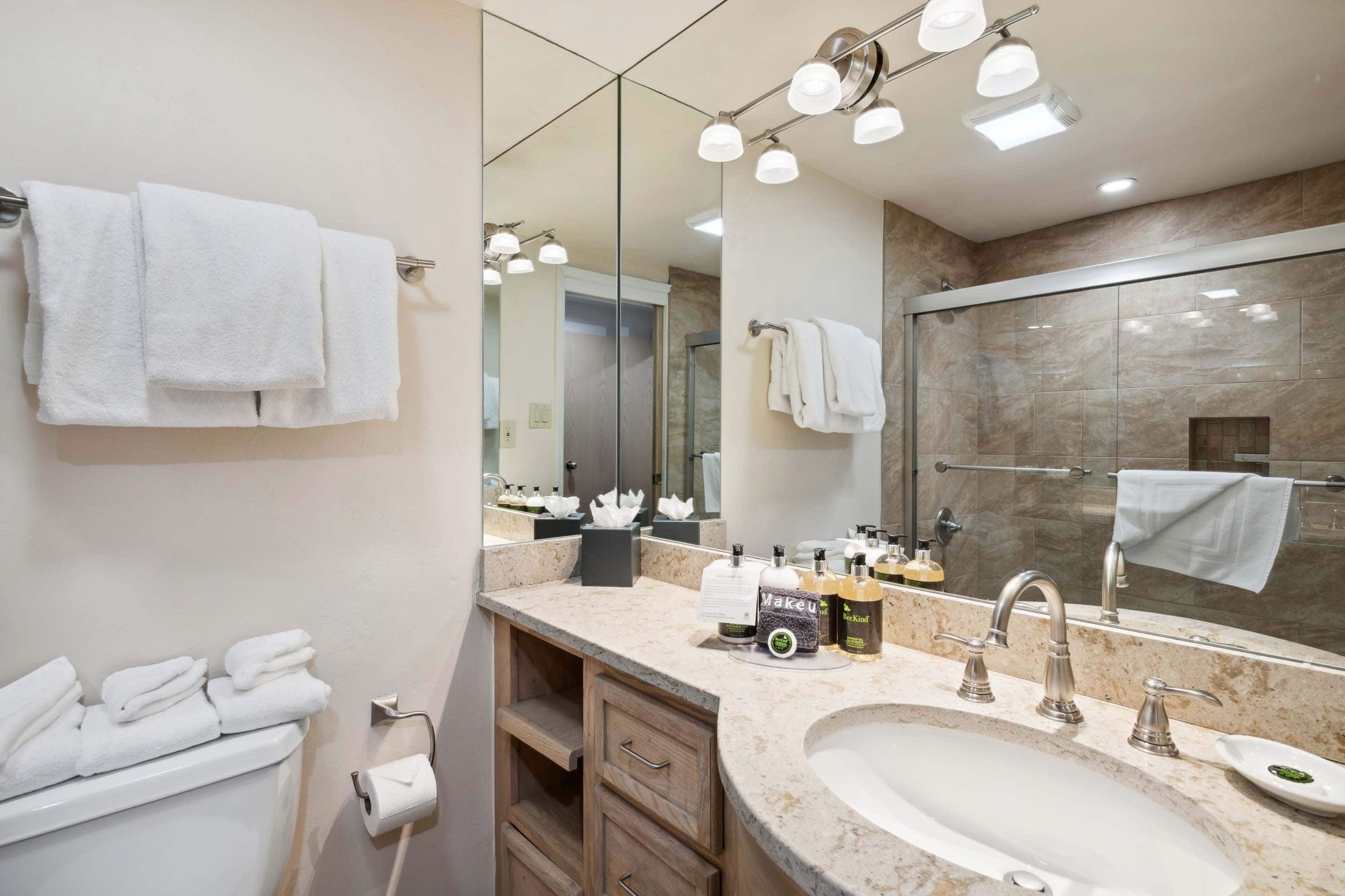 A modern bathroom with a large mirror, a sink, and a shower area.