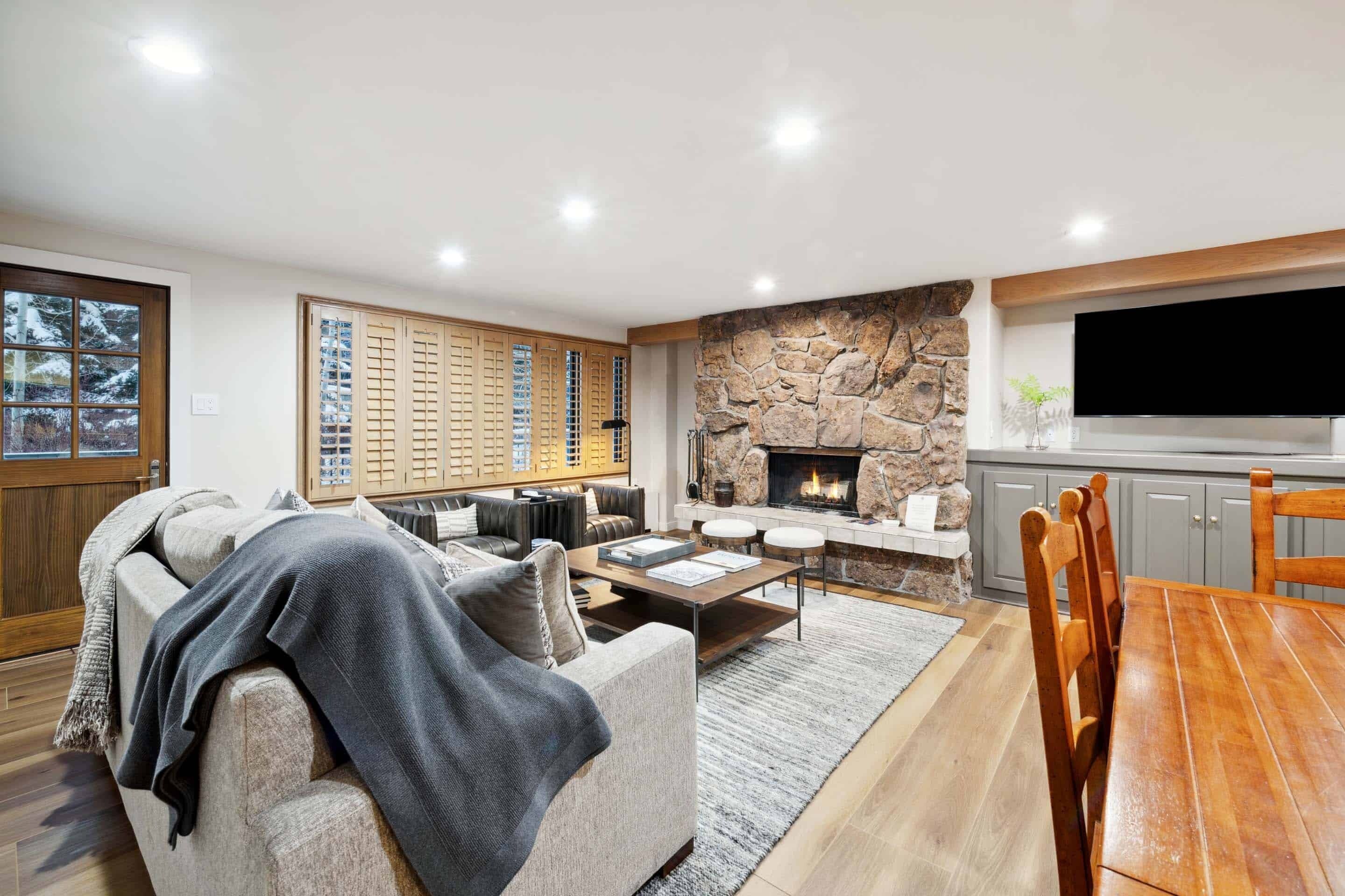 A modern living room with a fireplace, a dining area, and a kitchen with a TV.