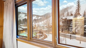 A window with a view of a snowy landscape, including trees and buildings.