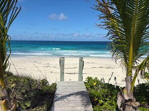 Un sentier en bois mène à une plage d’où l’on a une vue dégagée sur l’océan.