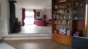 Un soggiorno con camino, una libreria, un divano rosso e una zona pranzo con tavolo e sedie.