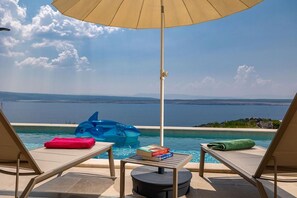 A poolside area with lounge chairs, a table with books, and a blue inflatable dolphin.