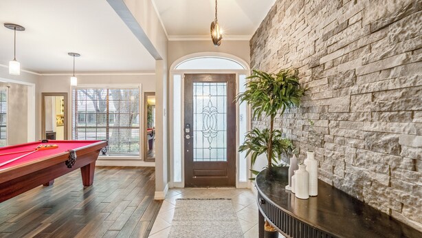 A pool table in a spacious room with a stone wall and a door with a decorative glass panel. - Spacious 4BR/2.5BA Houston Home, Pool, WiFi & AC Included (Houston)