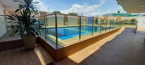 A rooftop swimming pool with glass railings, surrounded by wooden decking and potted plants. - Hotel Fenix (Aracaju)