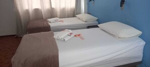 A hotel room with two single beds, each with a white bedspread and a rolled towel. - Hotel Fenix (Aracaju)