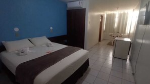 A hotel room with a bed, a desk, a chair, and a small kitchenette. - Hotel Fenix (Aracaju)