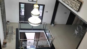 A multi-level interior with a central staircase, a chandelier, and decorative wall art. - Glen Mist (Kodaikanal)