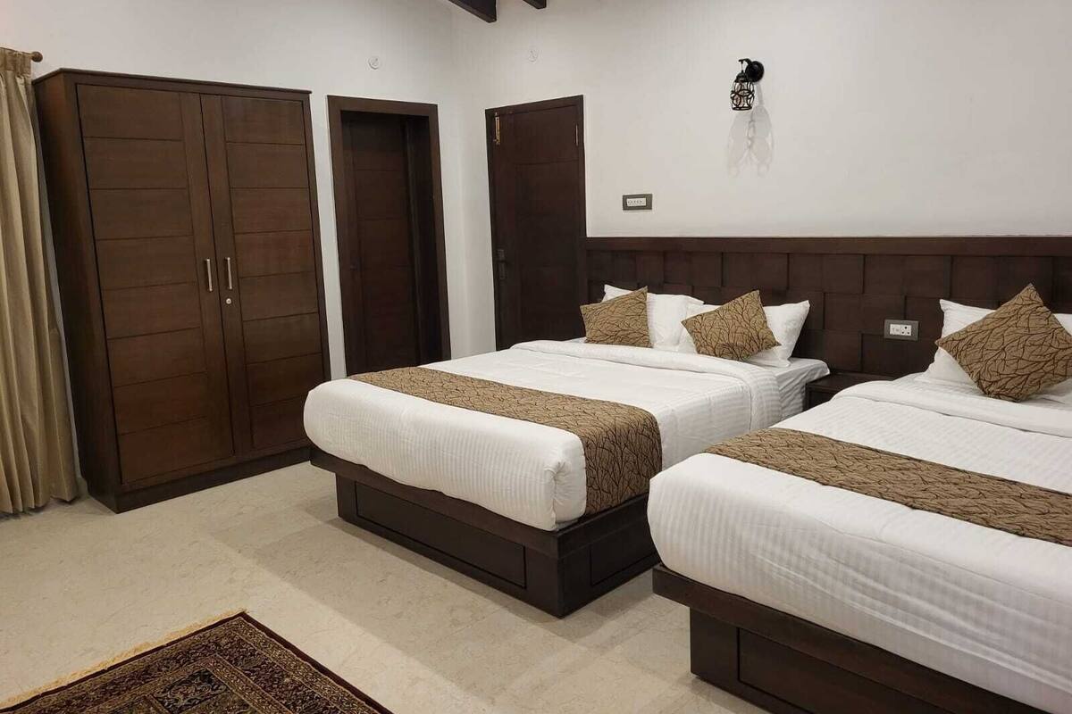 A hotel room with two beds, a wardrobe, and a nightstand.