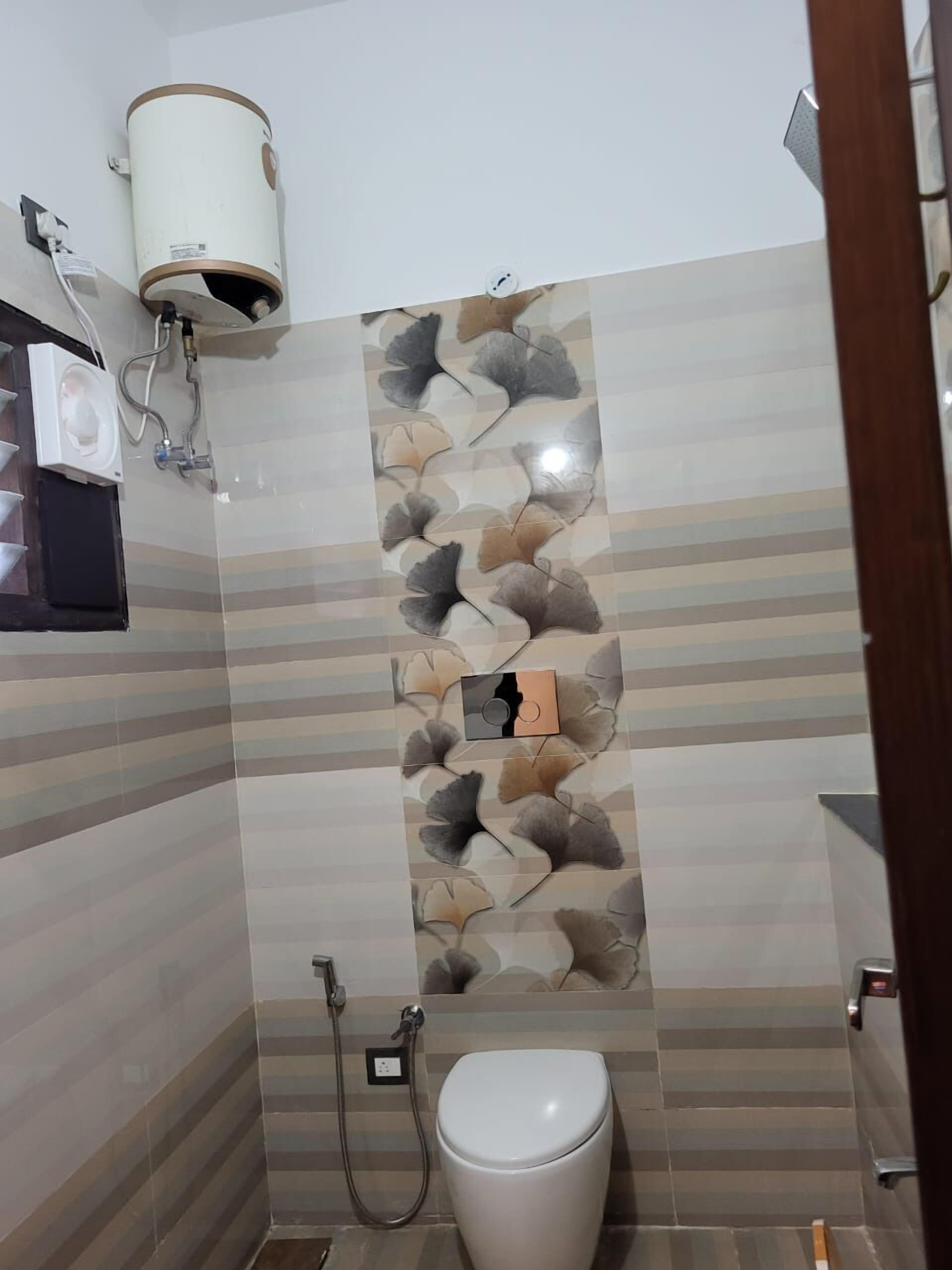 A bathroom with a toilet, a wall-mounted heater, and a shower.