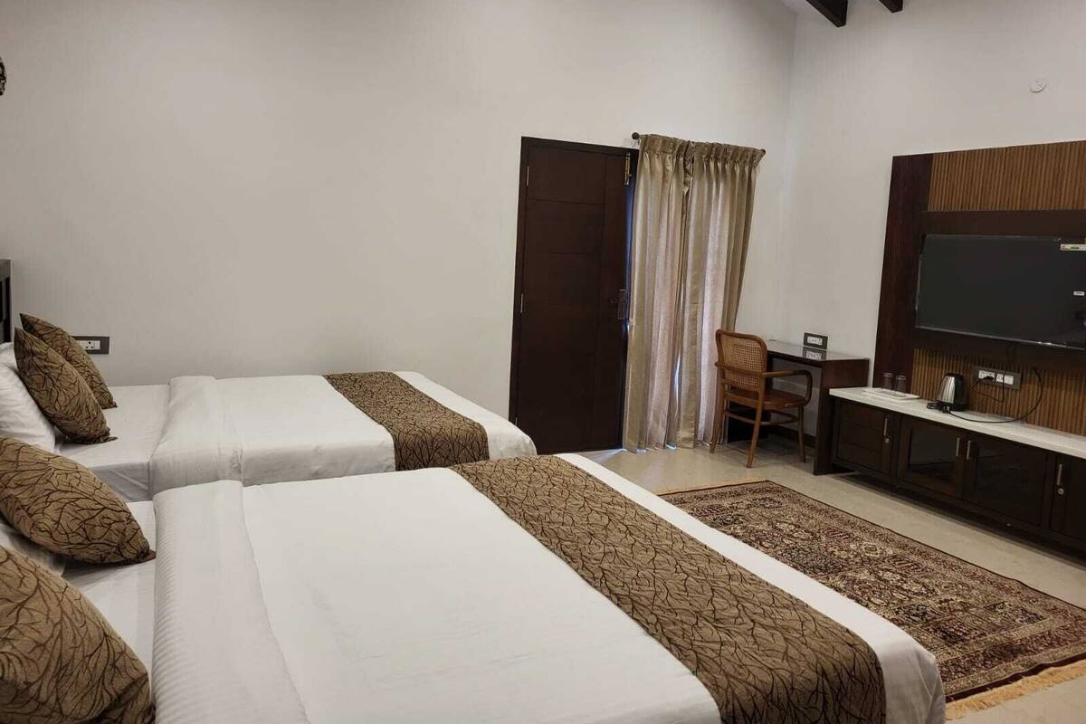 A hotel room with two beds, a TV, a desk, and a chair.