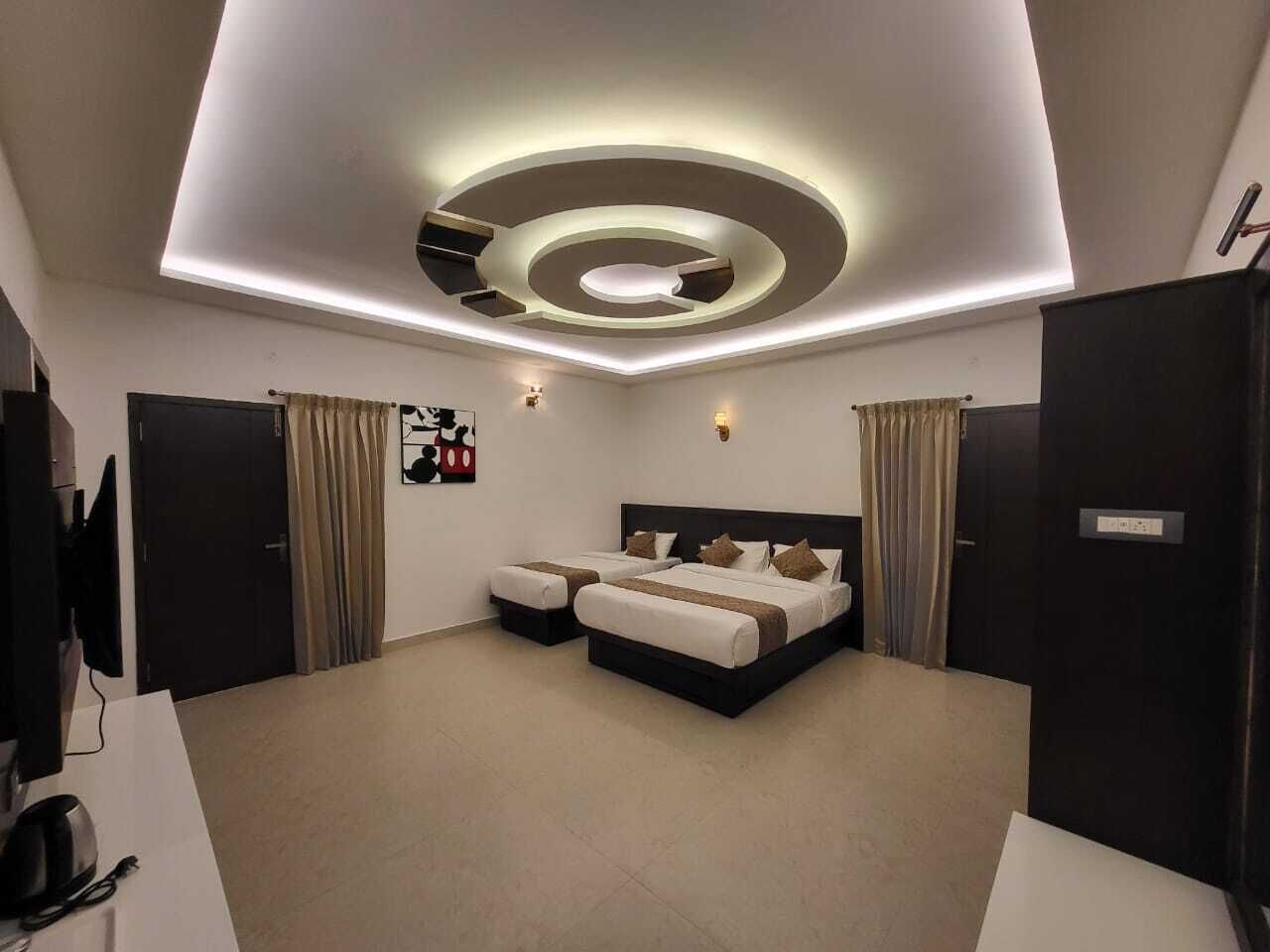 A modern bedroom with a large bed, two bedside tables, a flat-screen TV, and a ceiling with circular lighting.