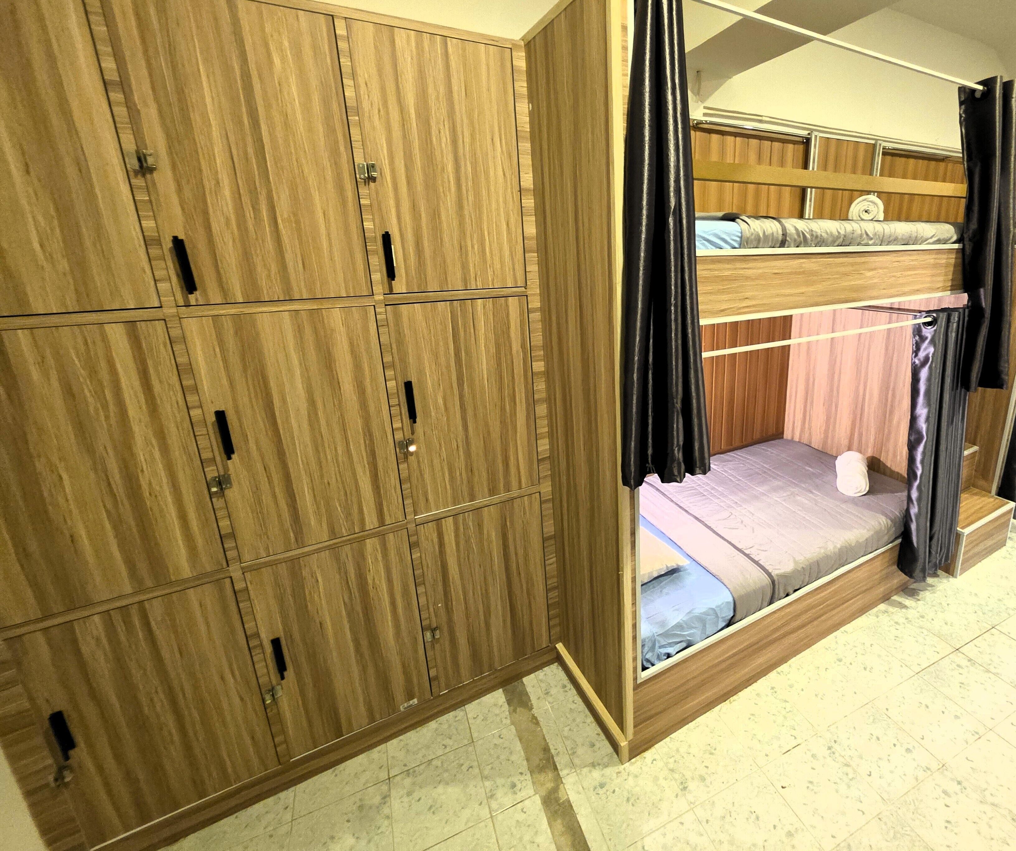 A room with a bunk bed, wooden wardrobe, and a curtain.