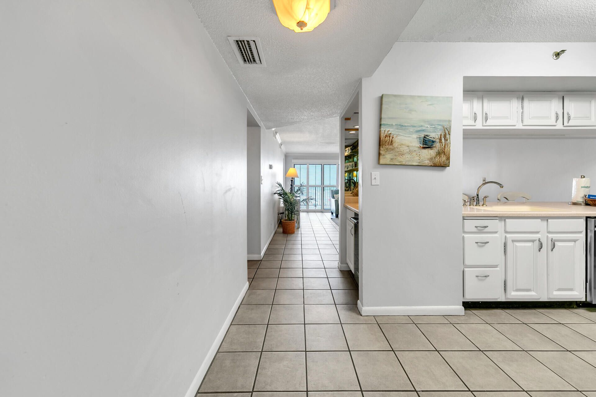 A kitchen with white cabinets, a sink, and a painting on the wall.