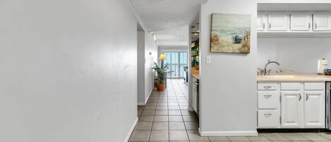 A kitchen with white cabinets, a sink, and a painting on the wall.