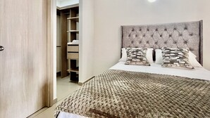 A bedroom with a large bed, a tufted headboard, and a built-in wardrobe.