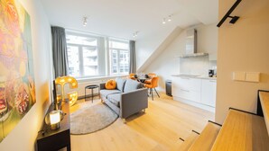Un salon moderne avec un canapé gris, une table à manger et une cuisine en arrière-plan.