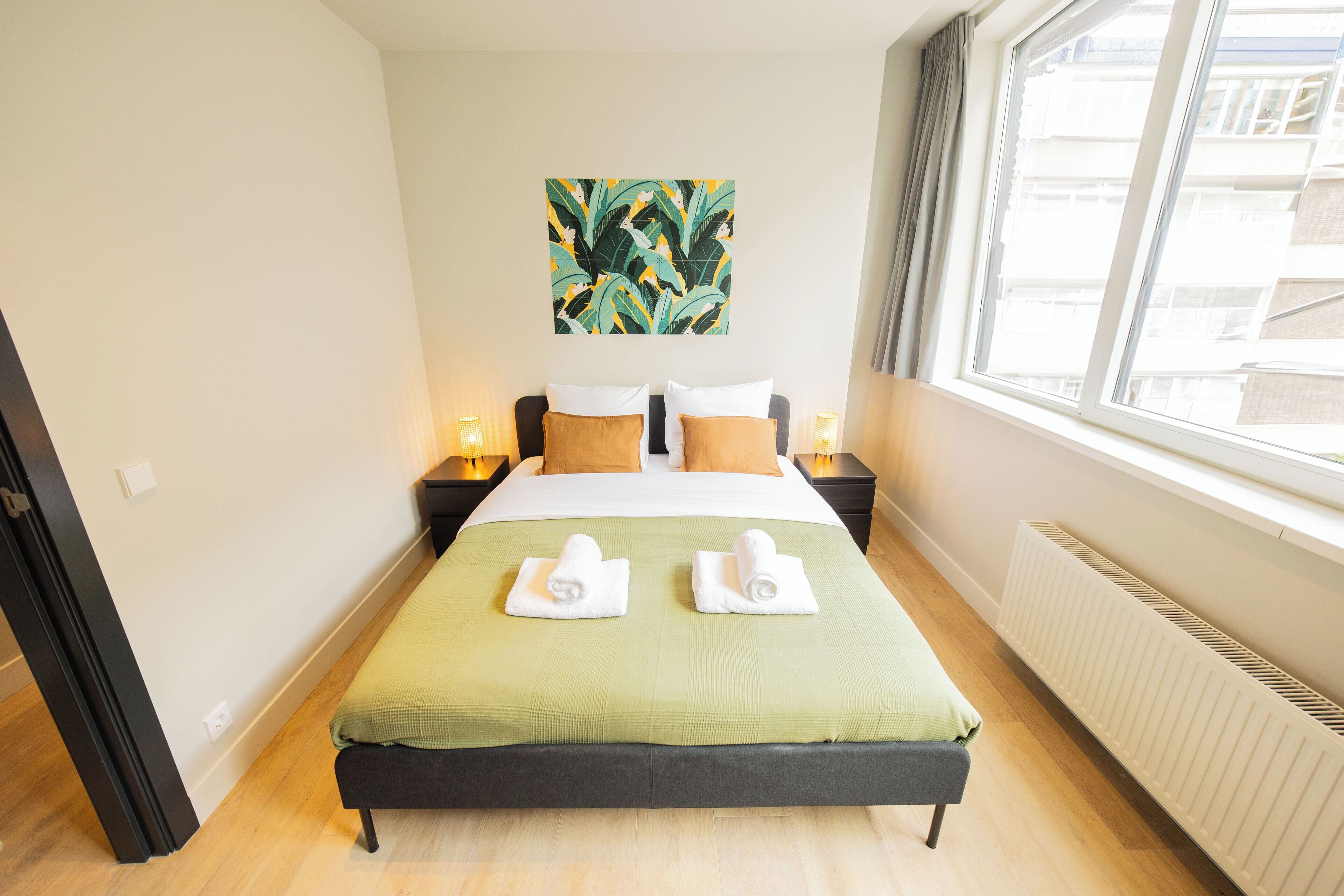 Ein Hotelzimmer mit einem Bett, zwei Nachttischen, einem Fenster und einer Heizung.