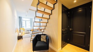 Un intérieur moderne avec un escalier, un fauteuil noir et une porte sombre.