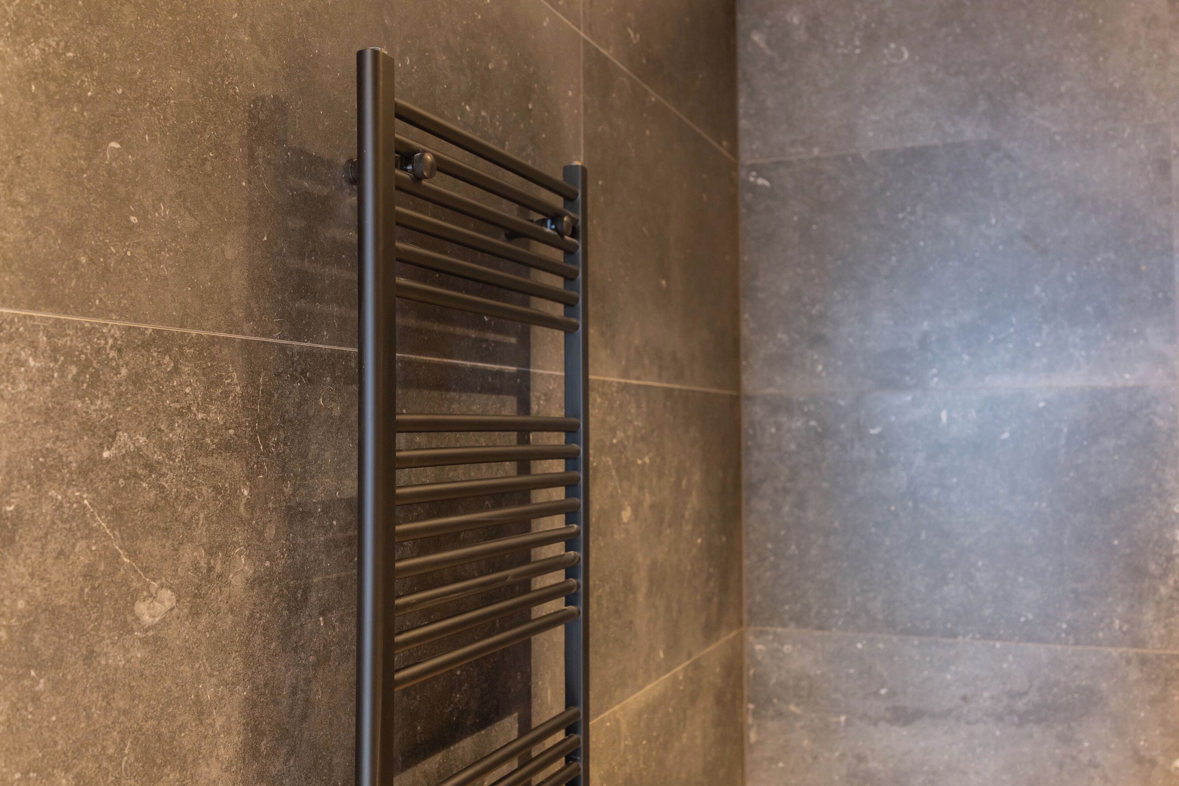 Un porte-serviettes noir fixé sur un mur recouvert de carreaux.
