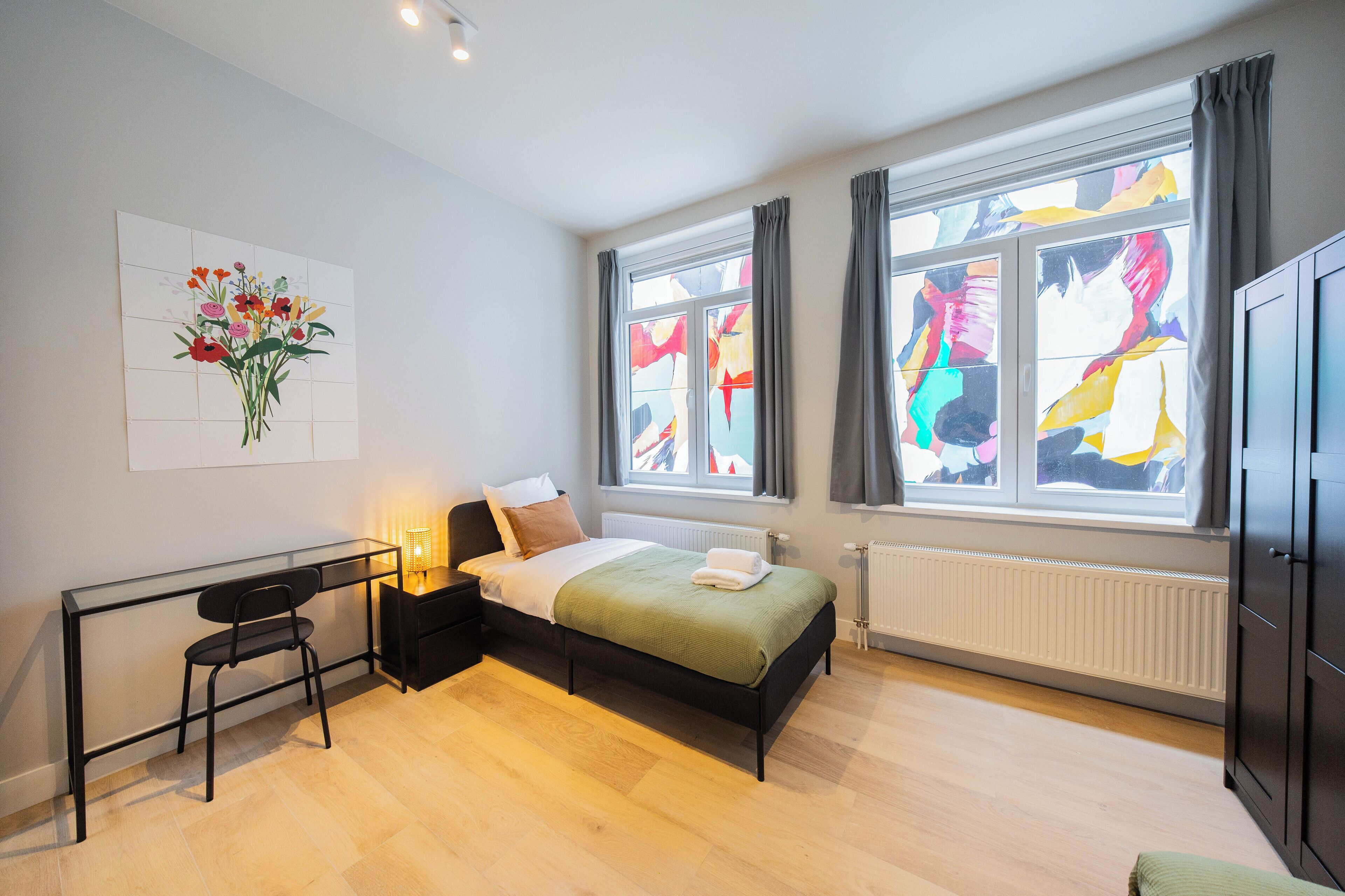 Een moderne slaapkamer met een bed, een bureau en een stoel.