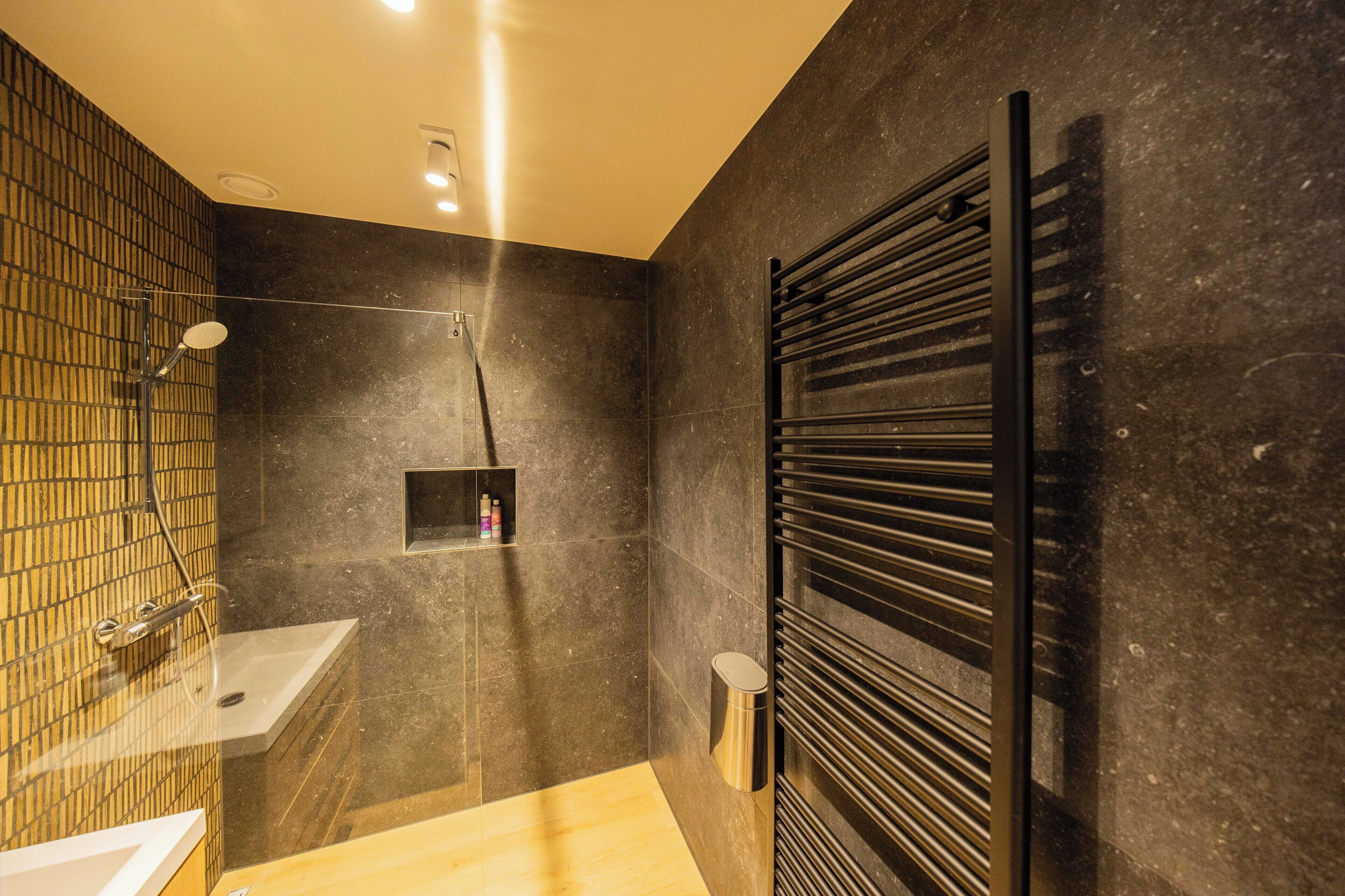 A modern bathroom with a shower, sink, and towel rack.