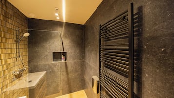 A modern bathroom with a shower, sink, and towel rack.