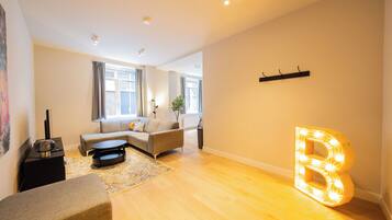 A modern living room with a sofa, a coffee table, and a large illuminated letter 'B'.