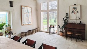 Une pièce spacieuse avec une grande fenêtre, un piano et plusieurs plantes en pot.