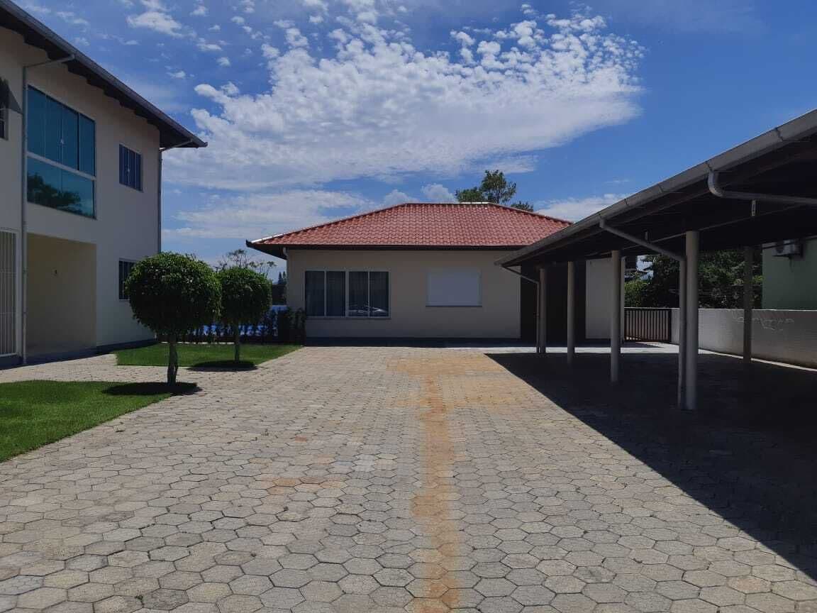 Un patio con suelo de baldosas, un área techada y un edificio con tejado rojo.