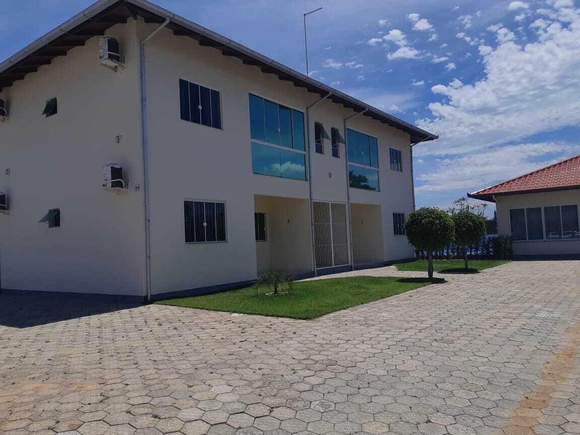 A two-story building with a flat roof, large windows, and a paved courtyard with hexagonal tiles.