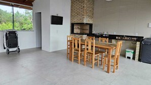 Eine Küche mit Backofen aus Ziegeln, einem Holztisch und -stühlen sowie einem Wagen.