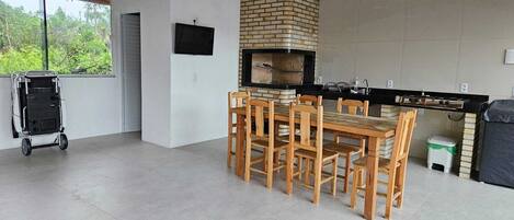 A kitchen with a brick oven, wooden table and chairs, and a cart.
