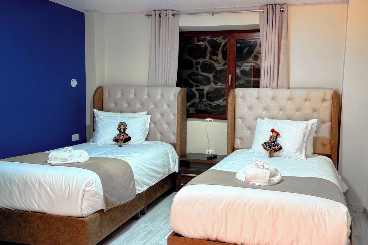 A hotel room with two beds, each with a headboard, white bedding, and decorative pillows.