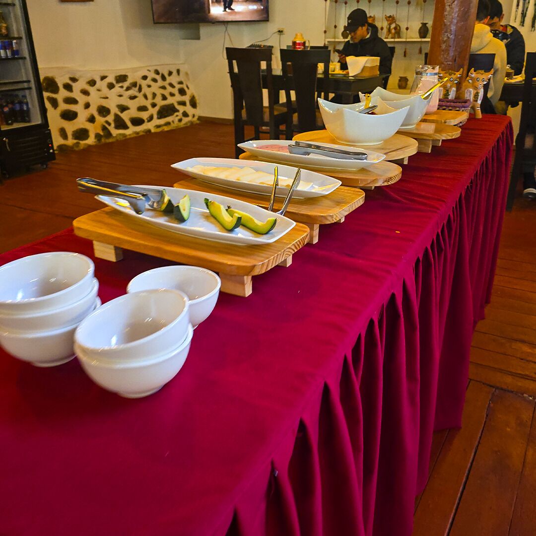 A buffet setup with multiple serving dishes and bowls on a red tablecloth.