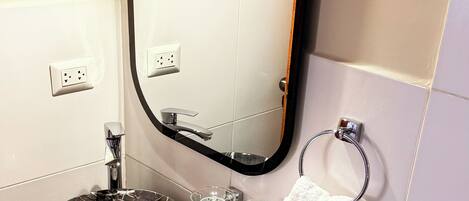 A bathroom with a black marble sink, a mirror, a towel rack, and a glass soap dish.