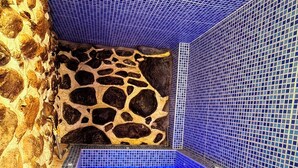 A small, tiled pool with a stone wall on one side and a blue-tiled wall on the other. - Andenes Del Inca (Ollantaytambo)