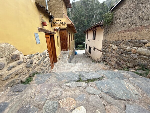 A narrow stone pathway leading to a building with a sign reading "Andenes Del Inca Hotel". - Andenes Del Inca (Ollantaytambo)