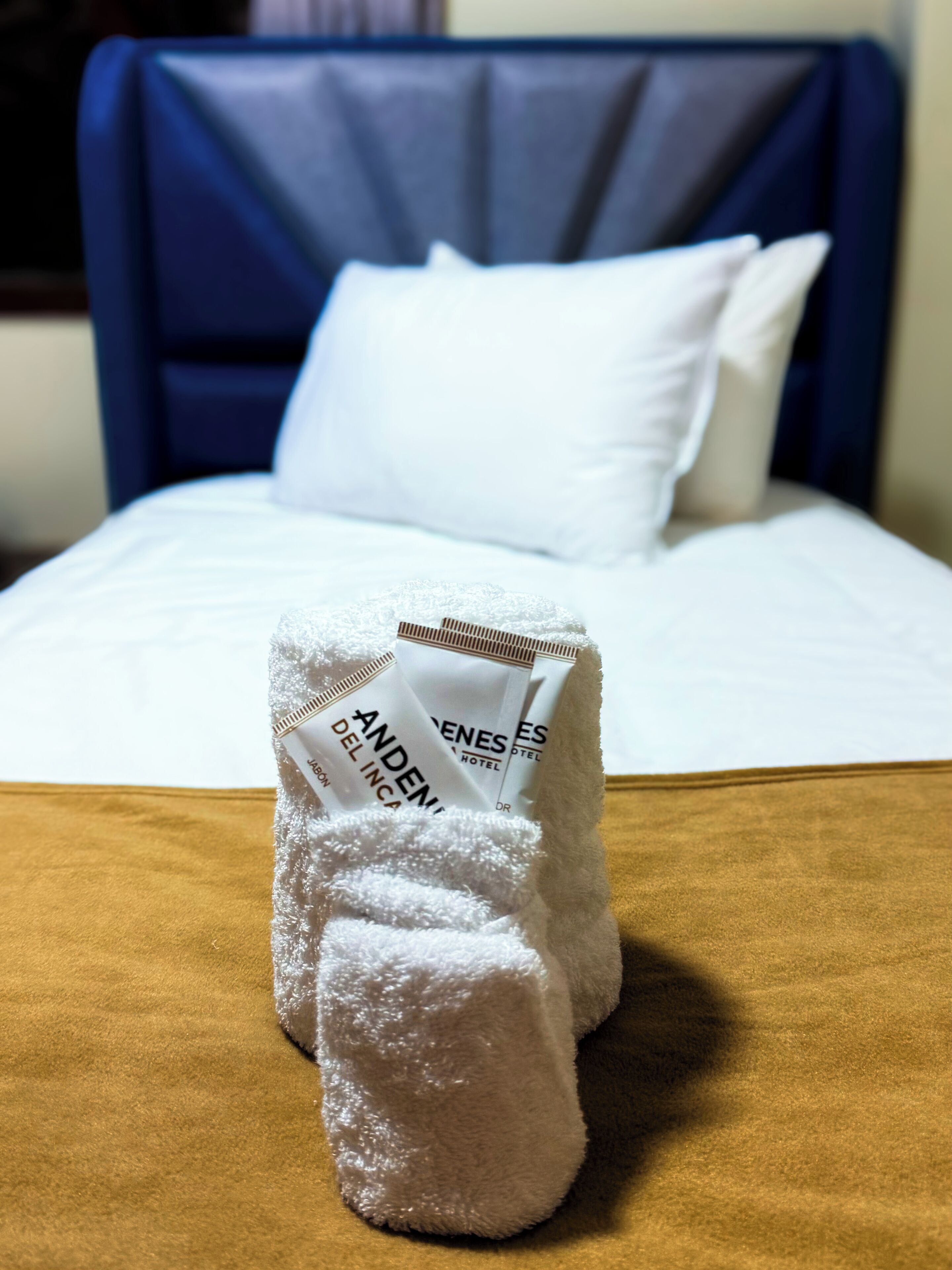 A neatly made bed with white linens and a blue headboard.