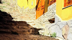 A narrow stone staircase leading to a yellow building with a sign reading "Andenes Del Inca Hotel".