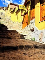 Una estrecha escalera de piedra que lleva a un edificio amarillo con un letrero que dice 'Andenes Del Inca Hotel'.