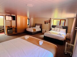 Habitación de hotel con dos camas, un escritorio, un armario y un radiador.