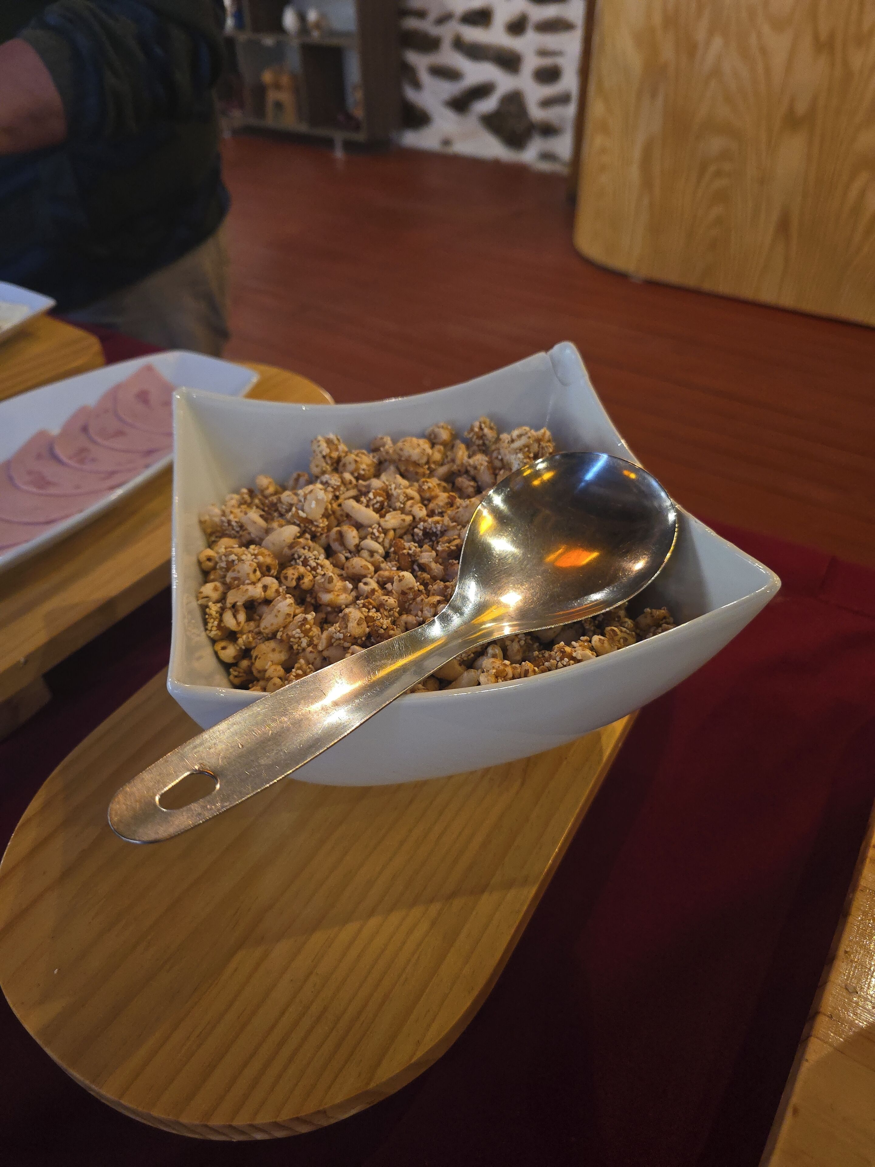 A bowl of granola with a spoon on a wooden table.