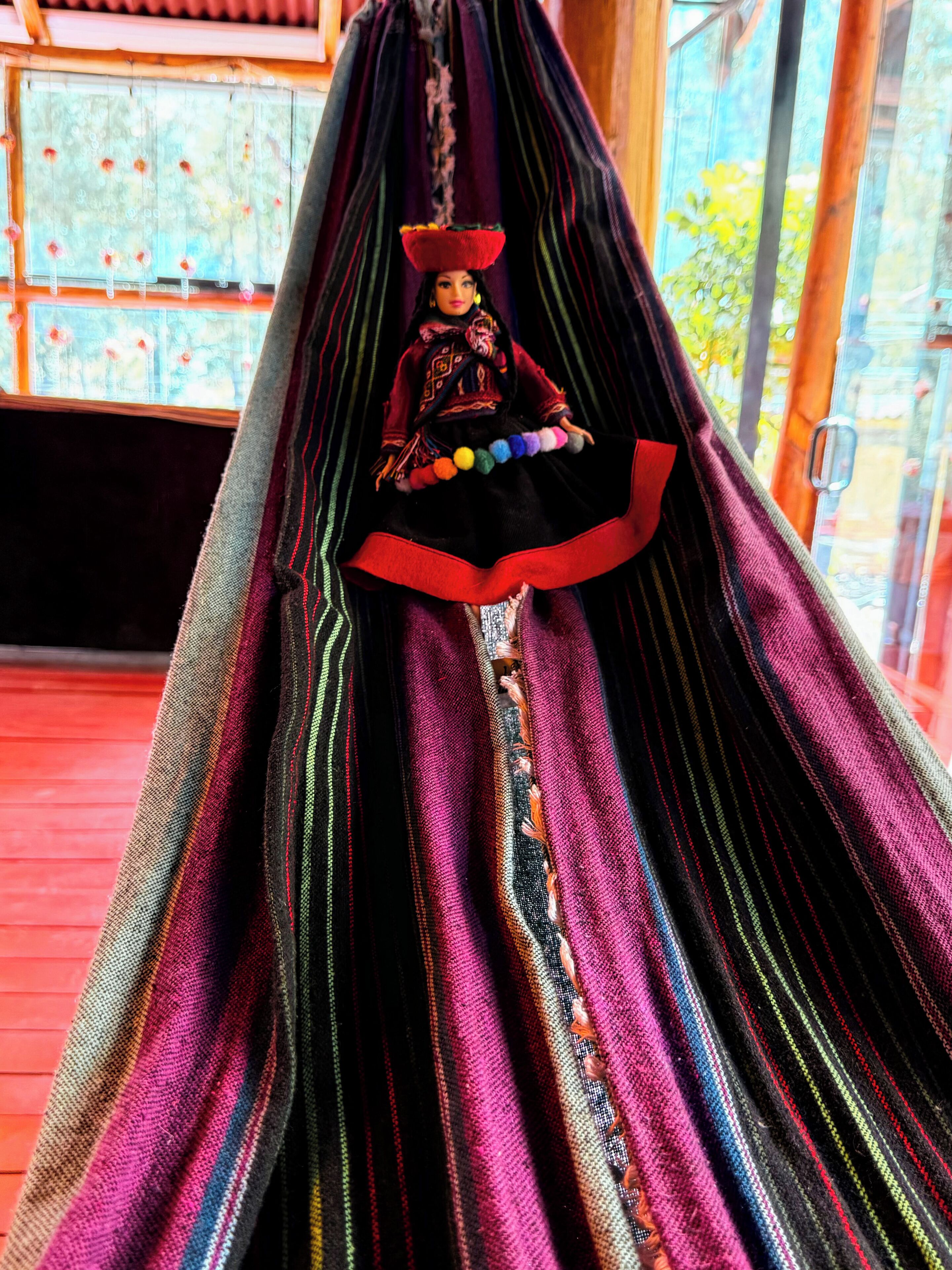 A hammock with a colorful, striped fabric and a decorative item hanging from it.