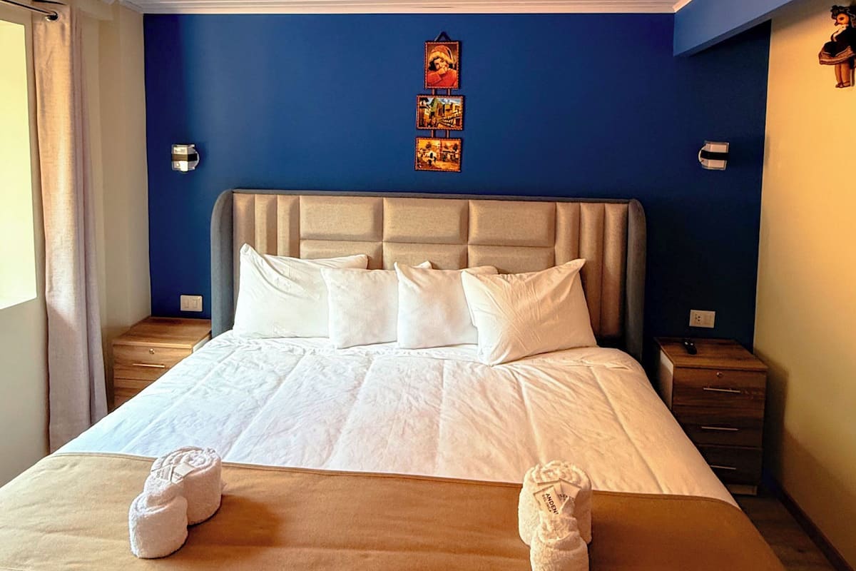 A neatly made bed with white linens and two towels on the bed.
