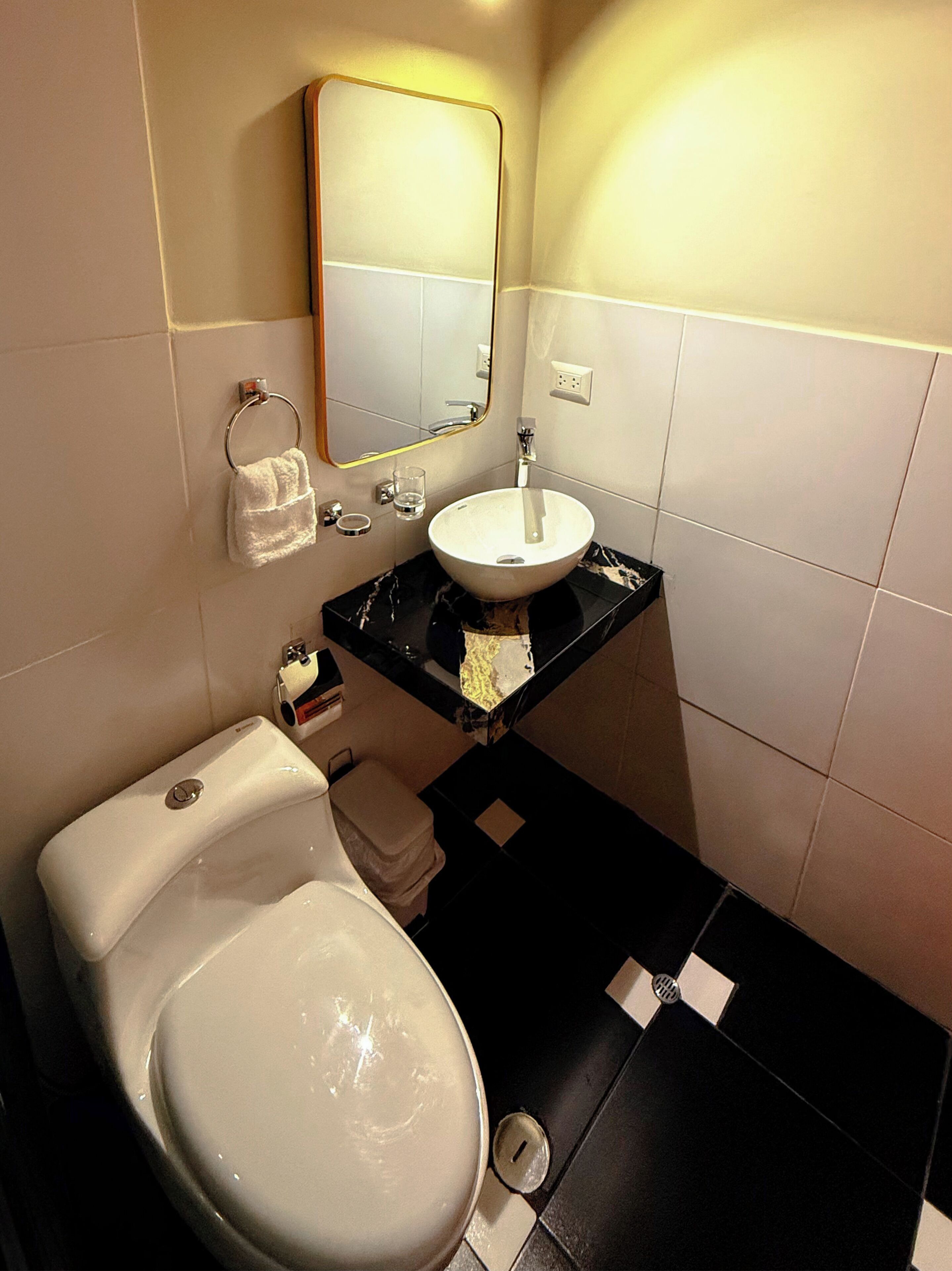 Ein modernes Badezimmer mit Toilette, Waschbecken und Spiegel.