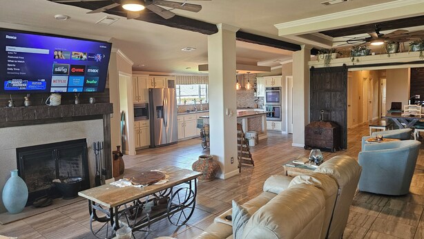A spacious living room with a fireplace, a large flat-screen TV mounted on the wall, and a cozy seating area with a sofa and a coffee table.
